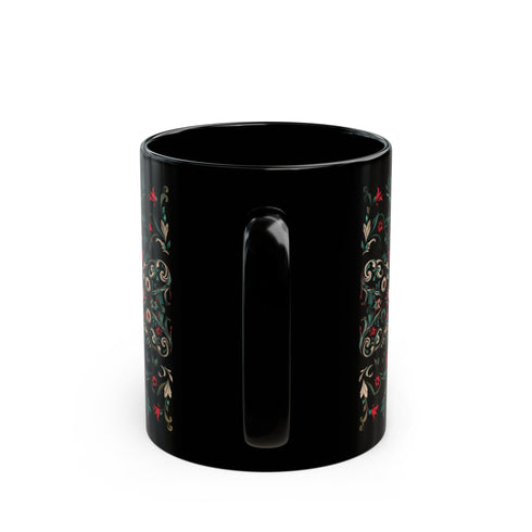 A black ceramic mug featuring a symmetrical folk art design with a central mystic eye motif in turquoise and coral. The design includes ornate scrollwork, red tulip-like flowers, sage green leaves, and cream flourishes arranged in a decorative pattern. The mug has a glossy finish with a C-shaped handle.